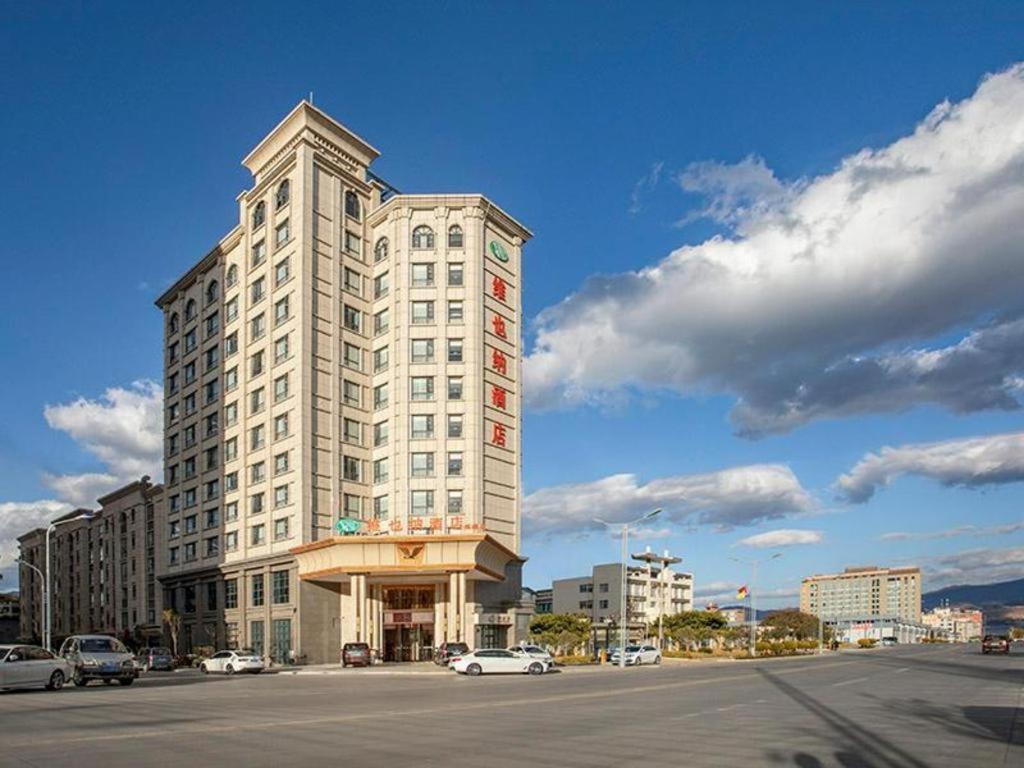un edificio blanco alto con coches estacionados en un estacionamiento en Vienna Hotel Yunnan Dali Erhai Lake en Dali