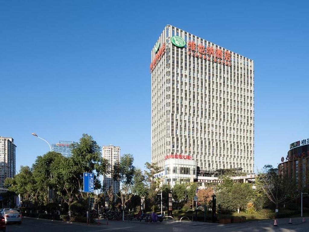 a tall building with a clock on the side of it at Vienna Hotel Kunming Dian Lake Wanda Plaza in Kunming
