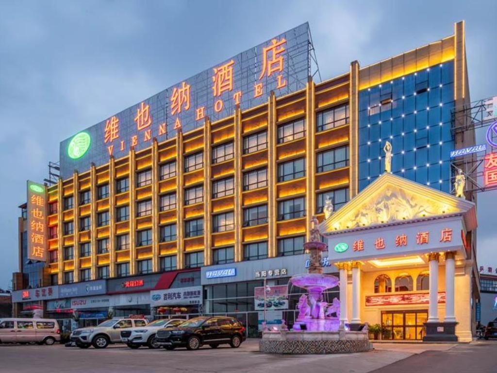 a large building with cars parked in front of it at Vienna Hotel Hubei Dangyang Bus Passenger Station in Dangyang