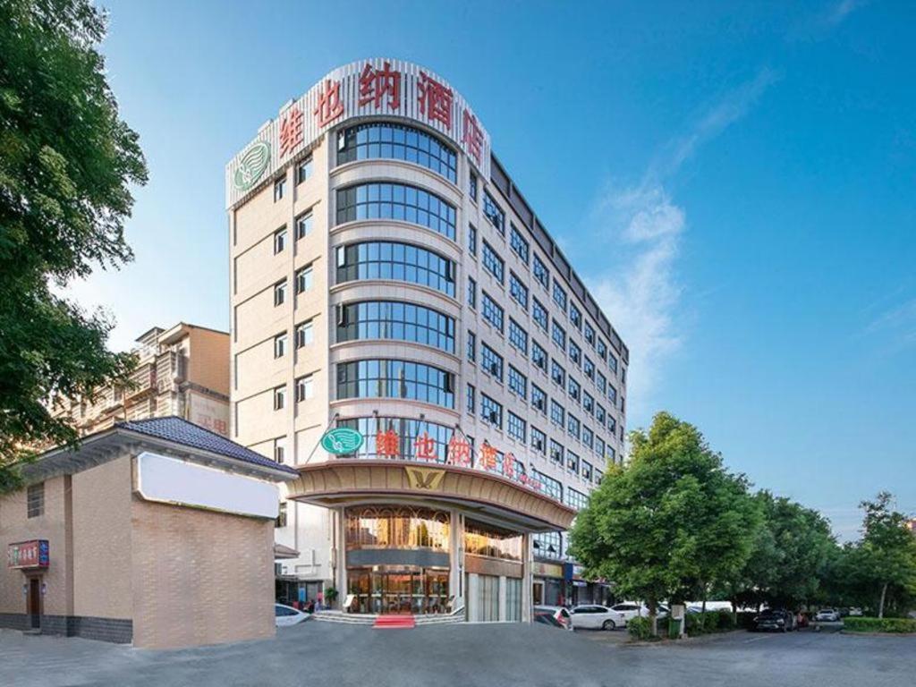 岳陽的住宿－Vienna Hotel Hunan Yueyang Bubugao，一座高大的白色建筑,上面有标志