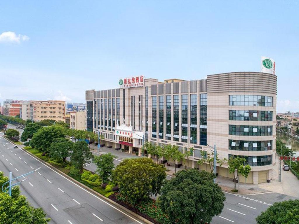 a large building on a street in a city at Vienna Hotel Guangdong Zhongshan Xiaolan High-Speed Railway Station in Jilong