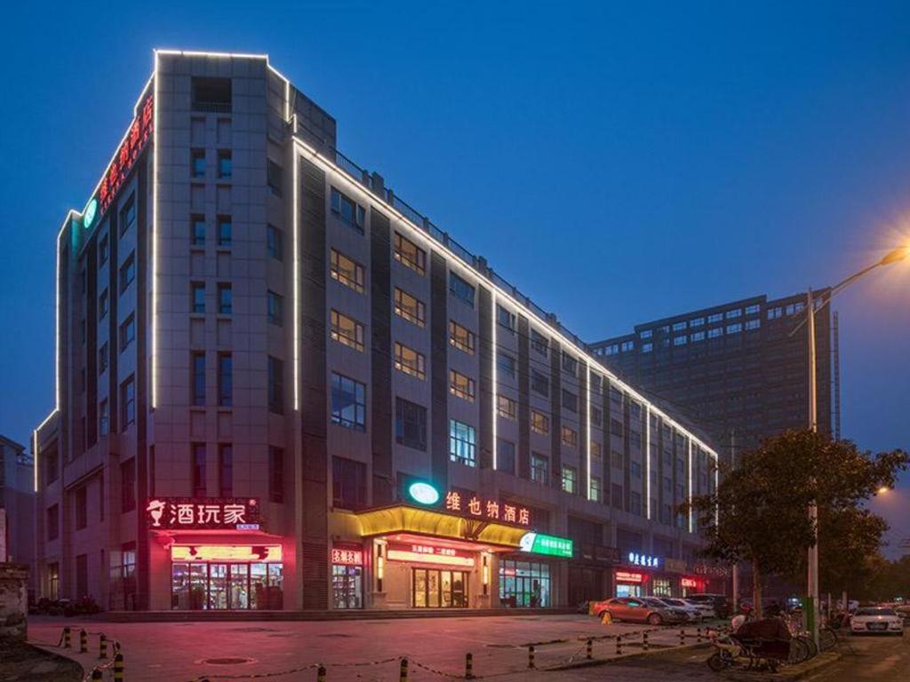 a large building with neon signs on the side of it at Vienna Hotel Xuzhou Junsheng Plaza Benteng Avenue Metro Station in Xuzhou