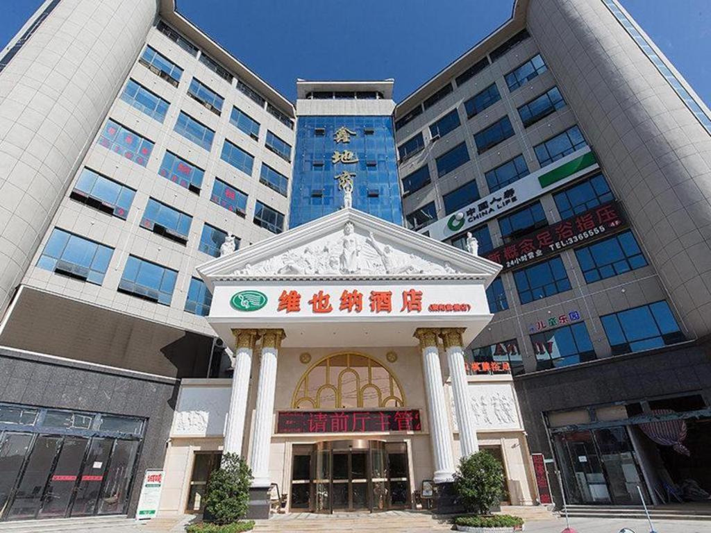 um edifício com uma torre de relógio em frente em Vienna Hotel Hubei Xiangyang Tang City Gulou em Xiangyang