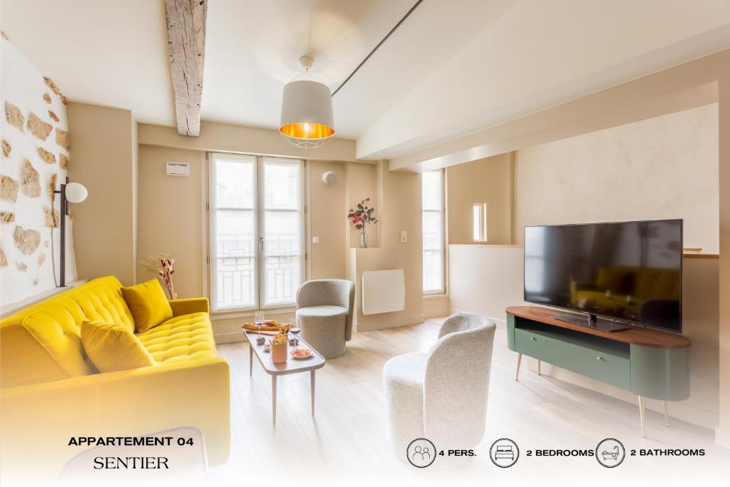 a living room with a yellow couch and a tv at Beauquartier - Sentier in Paris