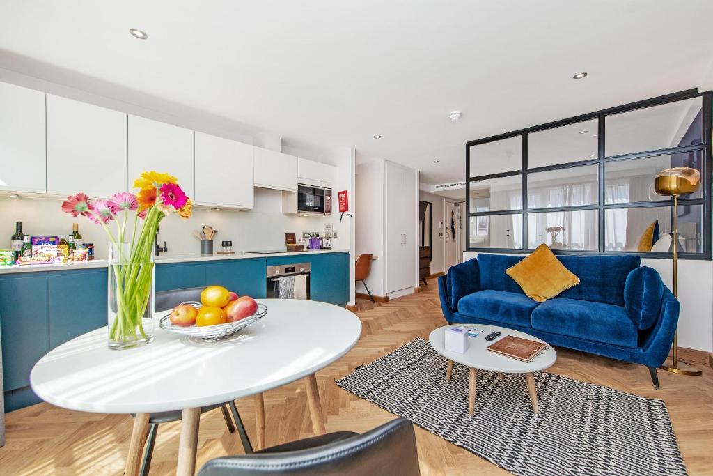 Farringdon Serviced Apartments في لندن: غرفة معيشة مع طاولة وأريكة زرقاء