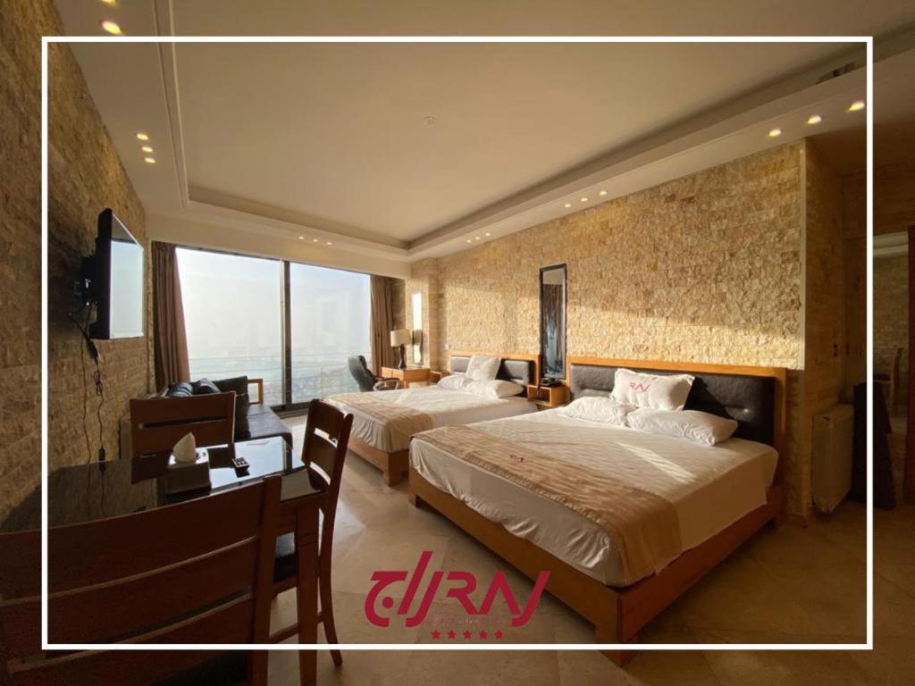 Pokój z 2 łóżkami, biurkiem i sypialnią w obiekcie Raj Hotel w mieście Alajh