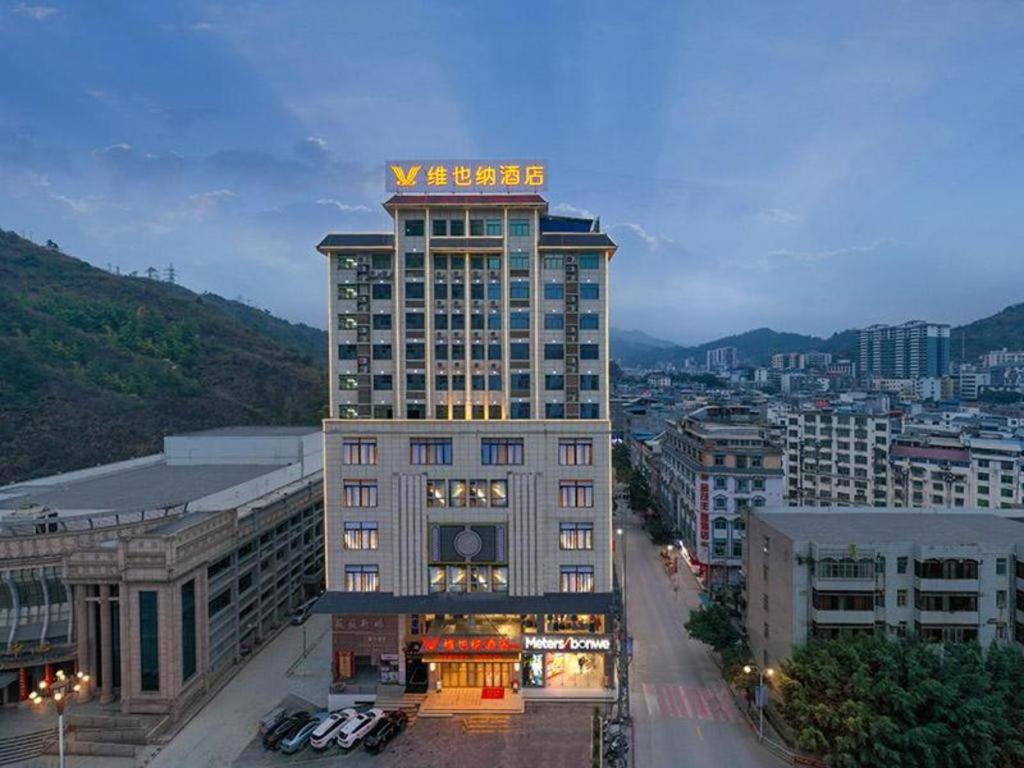 a tall building with a sign on top of it at Vienna Hotel Guangxi Baise Xilin County Juting Cultural Arts Center 