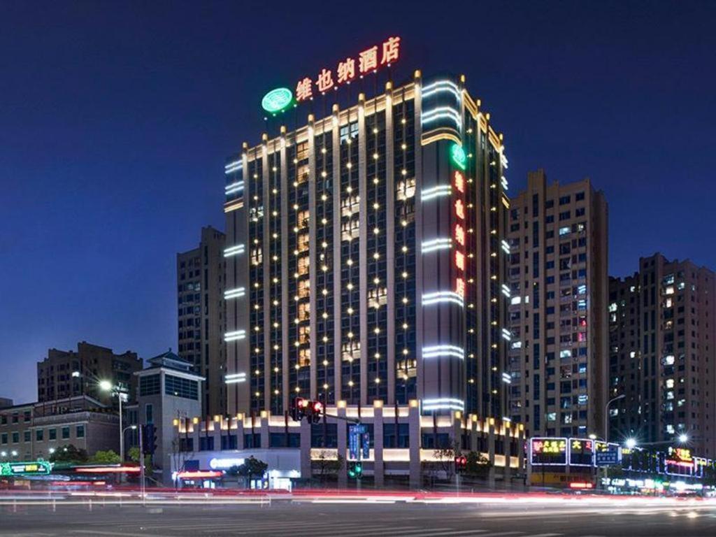 Vienna Hotel Fujian Yong'an South Railway Station في Yong'an: مبنى كبير مع أضواء عليه في الليل