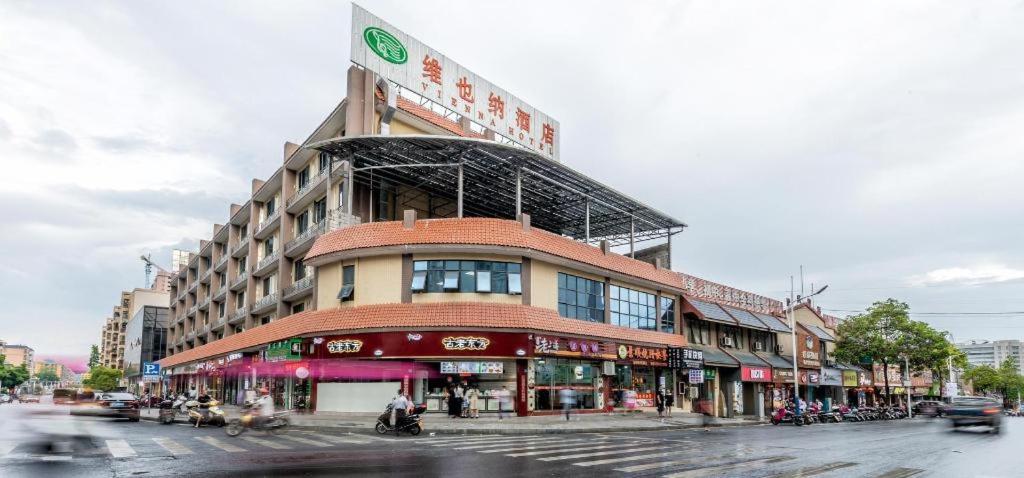 a building on the corner of a busy city street at Vienna Hotel Guangdong Shaoguan Ruyuan Yao Cultural Square in Shaoguan