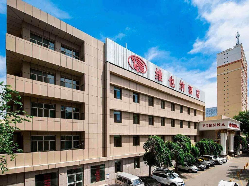 un edificio con auto parcheggiate in un parcheggio di Vienna Hotel Urumqi Railway Administration Academy of Sciences a Ürümqi