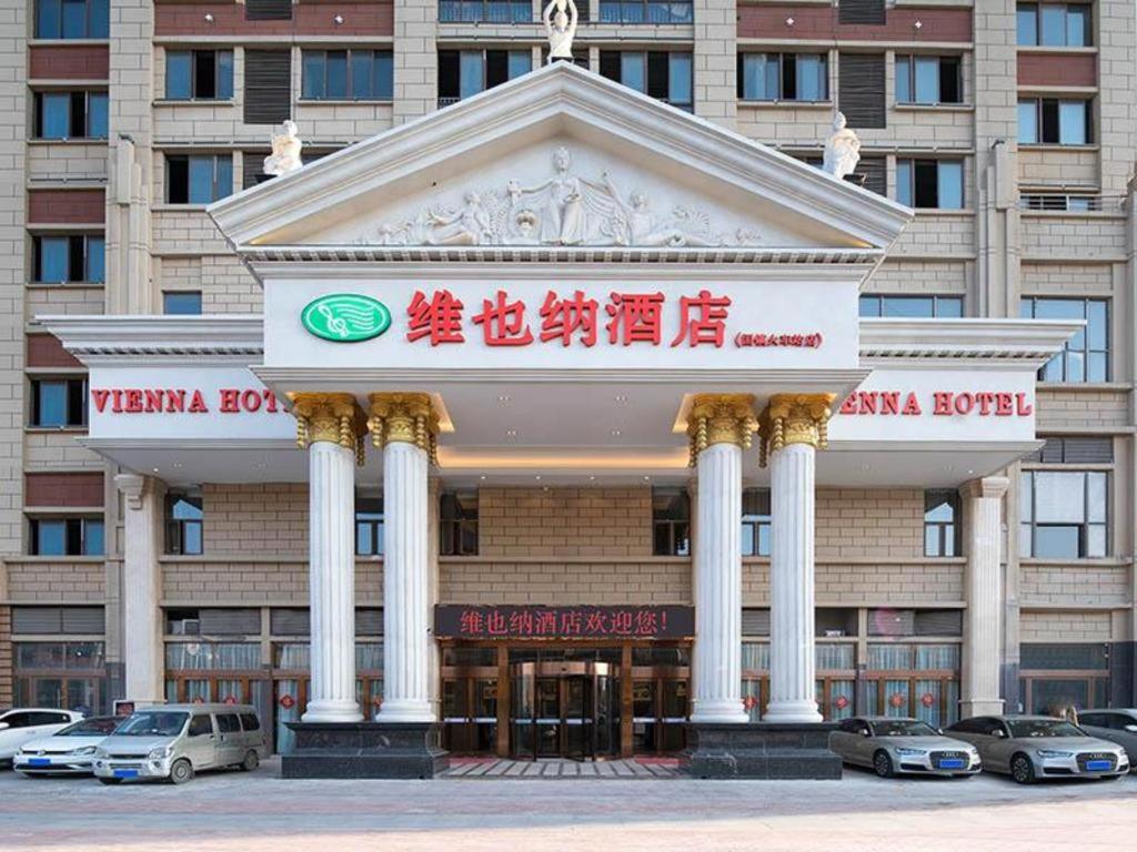 un edificio con coches estacionados frente a él en Vienna Hotel Anhui Bengbu Guzhen Railway Station en Qiaokou