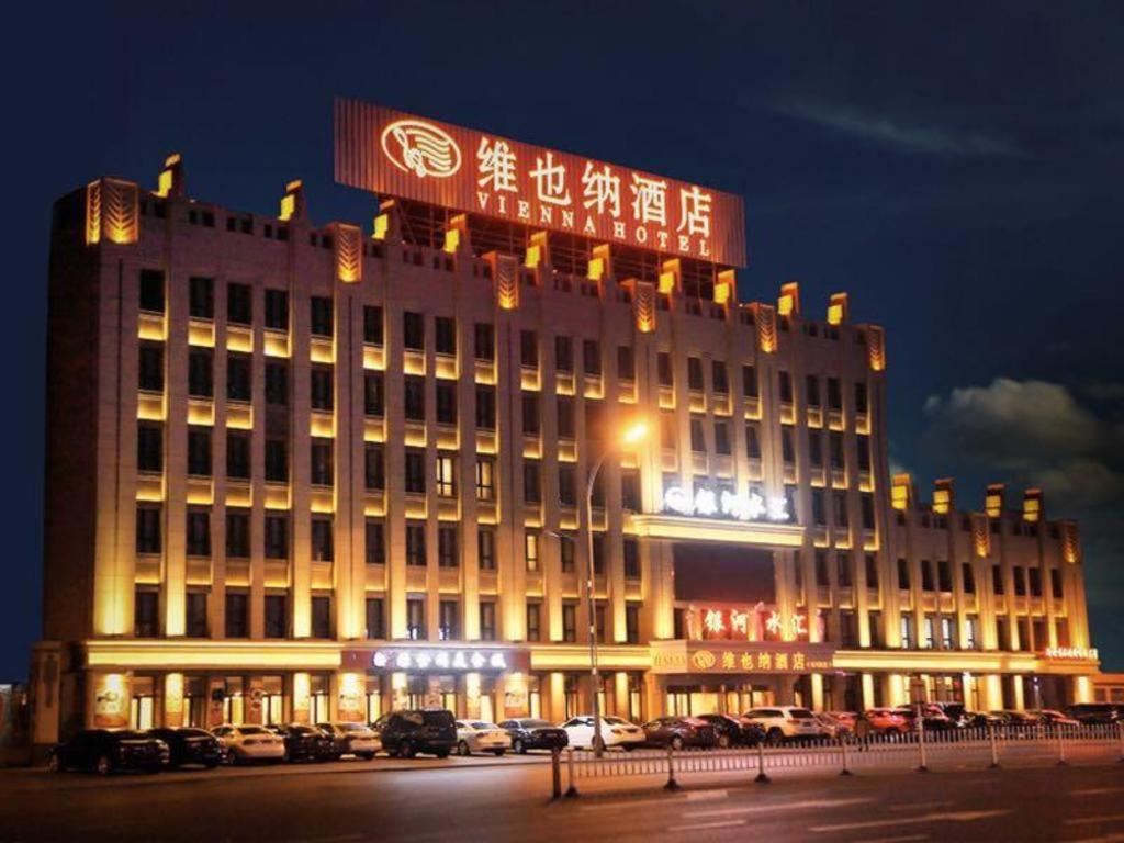 ein Gebäude mit einem Schild darüber in der Nacht in der Unterkunft Vienna Hotel Heilongjiang Qiqihar South Road in Qiqihar