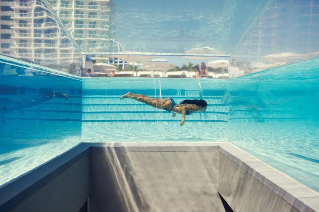 un uomo che nuota in una piscina in un edificio di SuitesRUs At W Hotel Fort Lauderdale a Fort Lauderdale