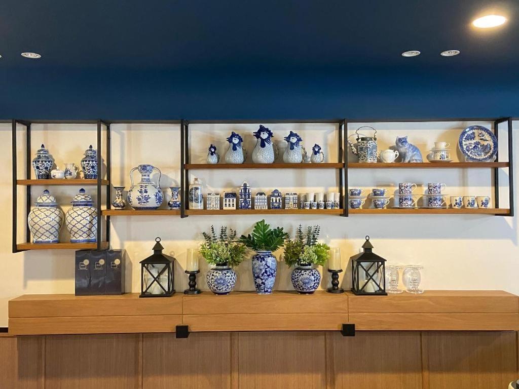 un estante lleno de jarrones azules y blancos en Eat Sleep Chann, en Chanthaburi