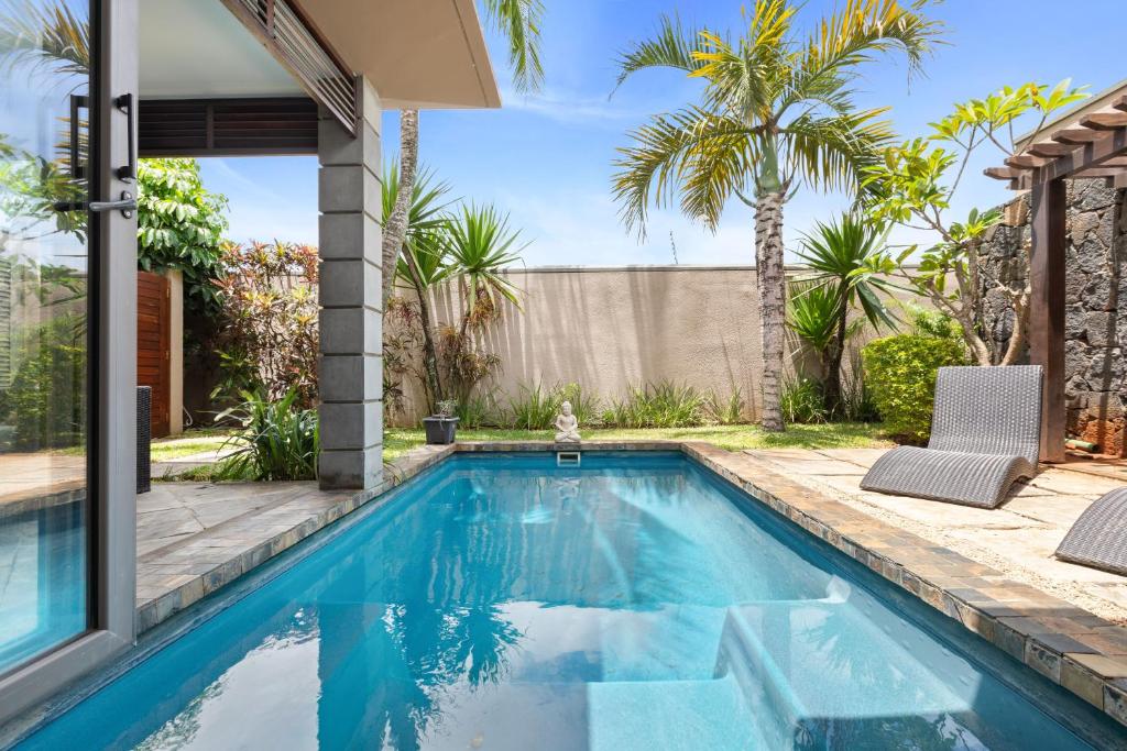 a swimming pool in the backyard of a home with palm trees at Athena Villa D10 in Pereybere