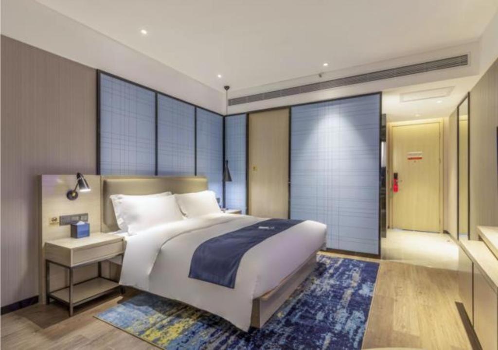 a bedroom with a large white bed and a desk at Echarm Hotel Quanzhou Liming Vocational University Ling Show World in Donghai