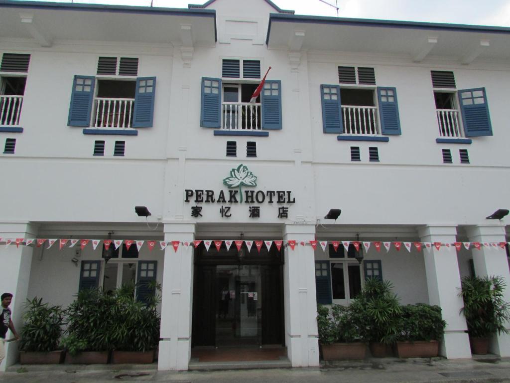 Un grand bâtiment blanc avec volets bleus dans l'établissement Perak Hotel, à Singapour