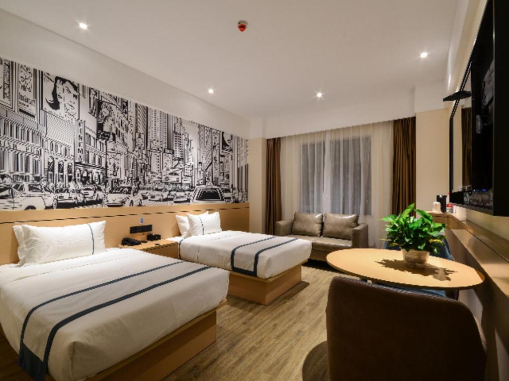une chambre d'hôtel avec deux lits et un canapé dans l'établissement City Comfort Inn Jingzhou Fantawild Shashi Middle School, à Juzhang He
