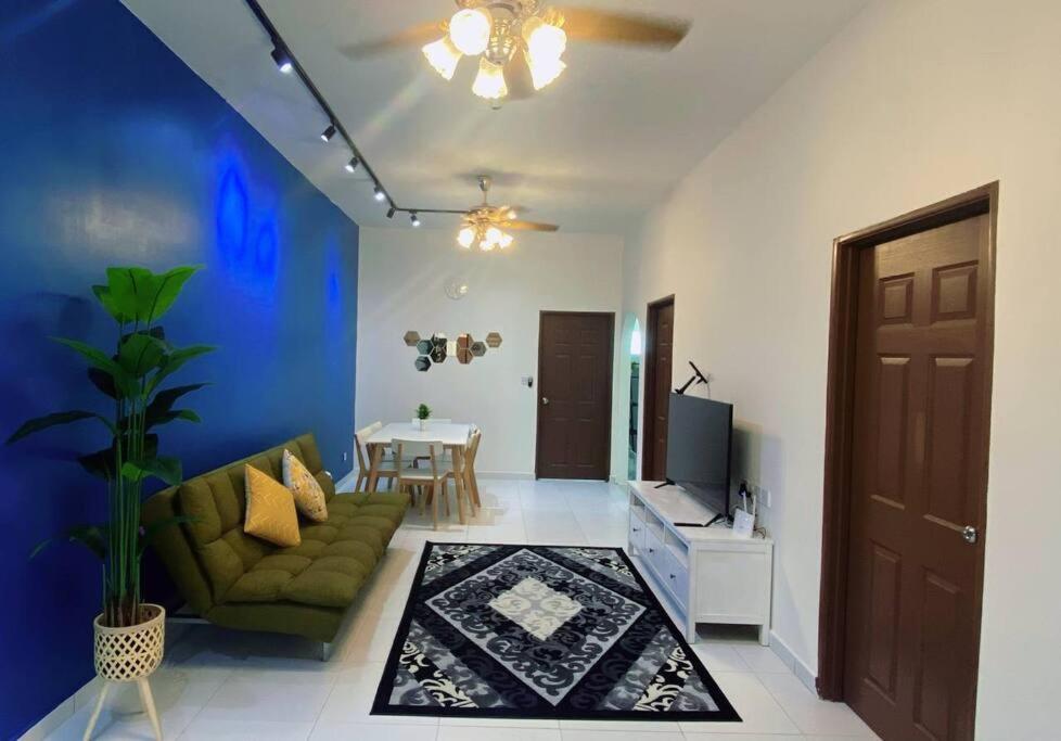 een woonkamer met een groene bank en een tv bij R&R Manjung Guest House at Pangsapuri Samudera in Seri Manjung