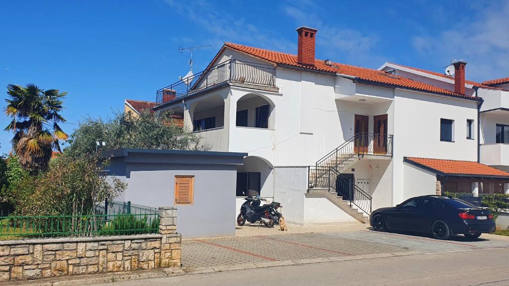 una casa blanca con una motocicleta estacionada frente a ella en Apartments Cintya en Poreč