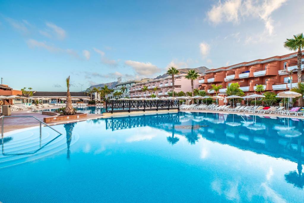 a large swimming pool at a resort with chairs and umbrellas at Landmar Costa los Gigantes in Puerto de Santiago