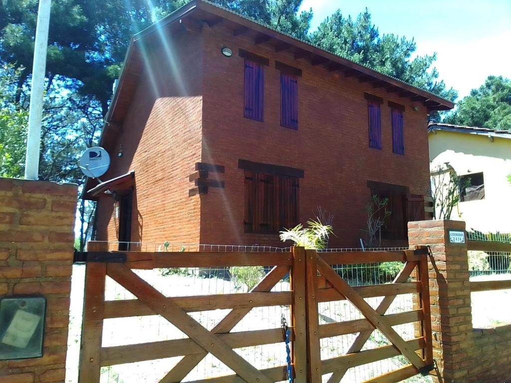 uma casa com janelas roxas e uma cerca de madeira em La casa del búho em Mar de Ajó