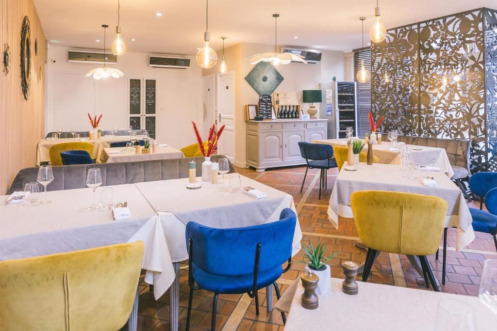 un restaurante con mesas blancas y sillas azules en LOGIS Hôtel & Restaurant Le Soleil D'or en Montigny-la-Resle