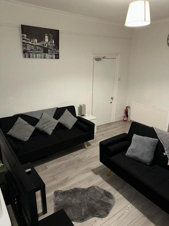 a living room with a black couch and a chair at Spacious 4 bedroom house in the city of London in London