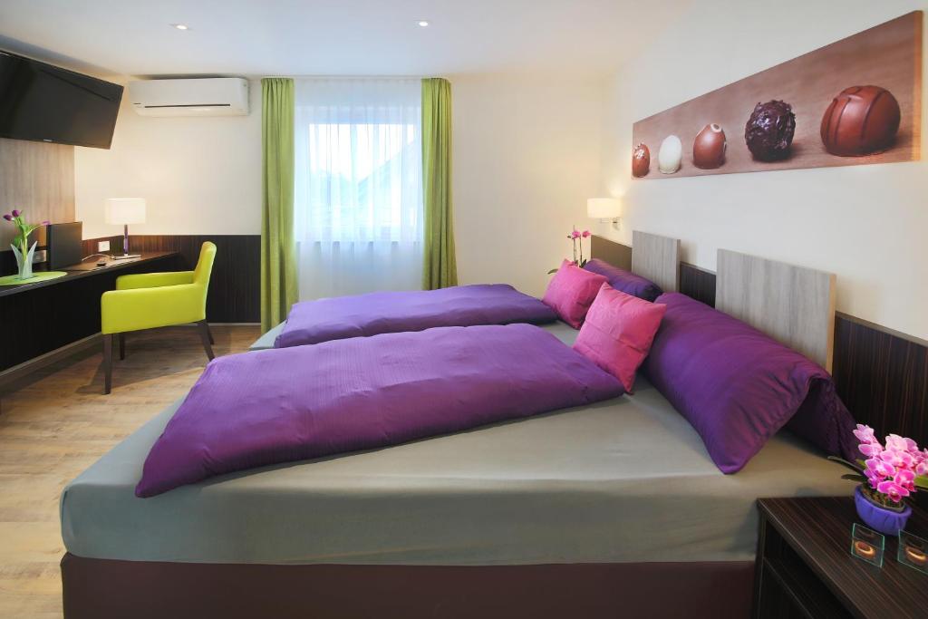 ein großes Bett mit lila Kissen im Schlafzimmer in der Unterkunft Hotel Gästehaus Stock Zimmer Trüffeleckle in Friedrichshafen