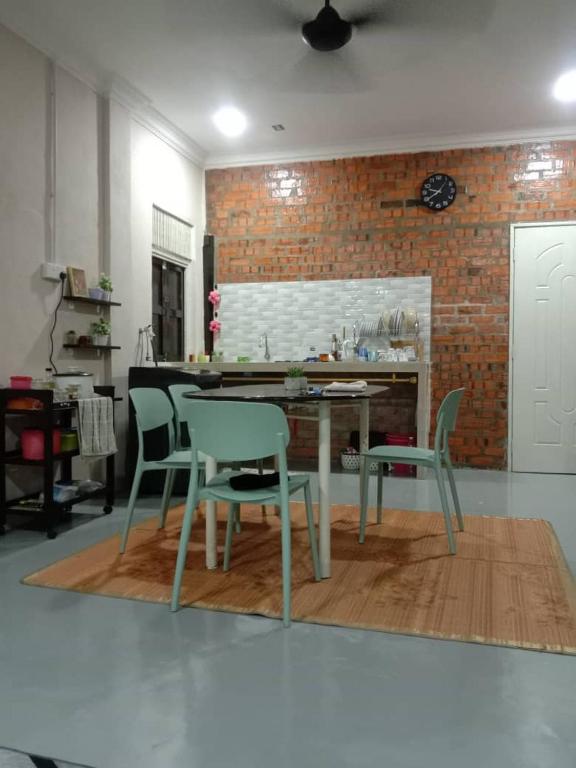 a dining room with a table and chairs and a brick wall at D GARDEN HOME STAY in Tanah Merah