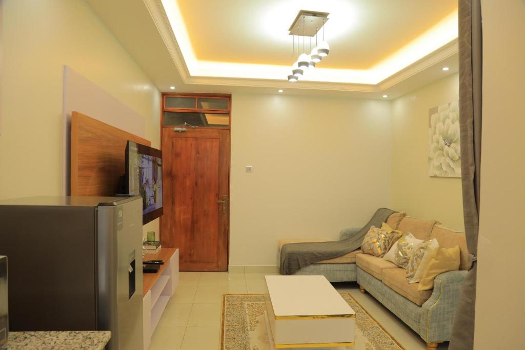 een woonkamer met een bank en een tv bij Gail Homes Naalya - One bedroom luxury apartment in Kampala
