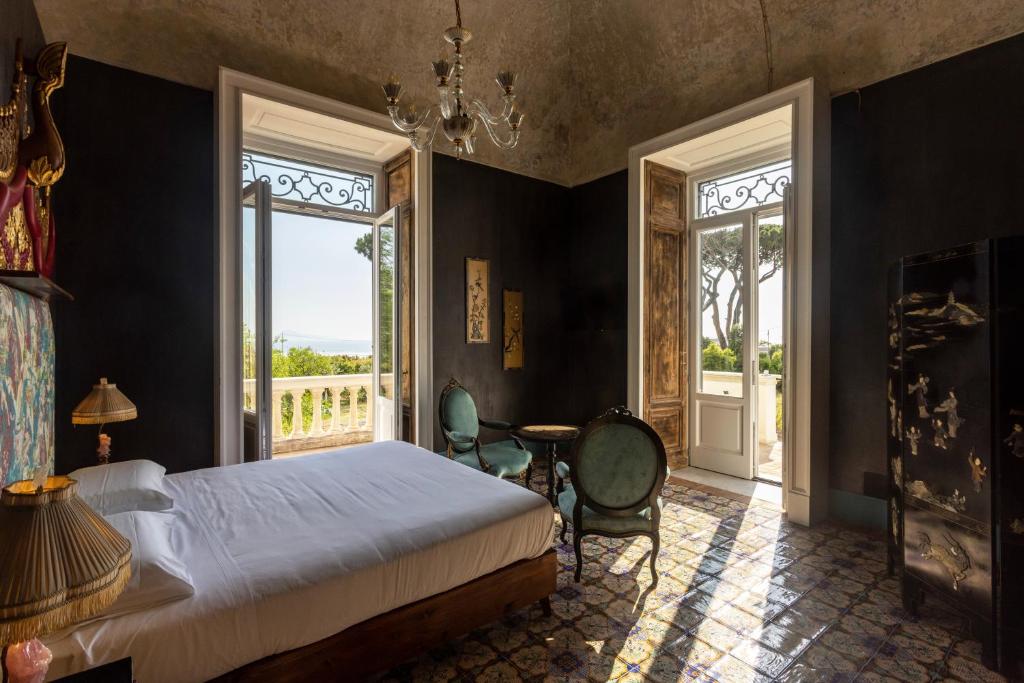 a bedroom with a bed and a table and windows at Villa De Cillis Carafa in Torre del Greco