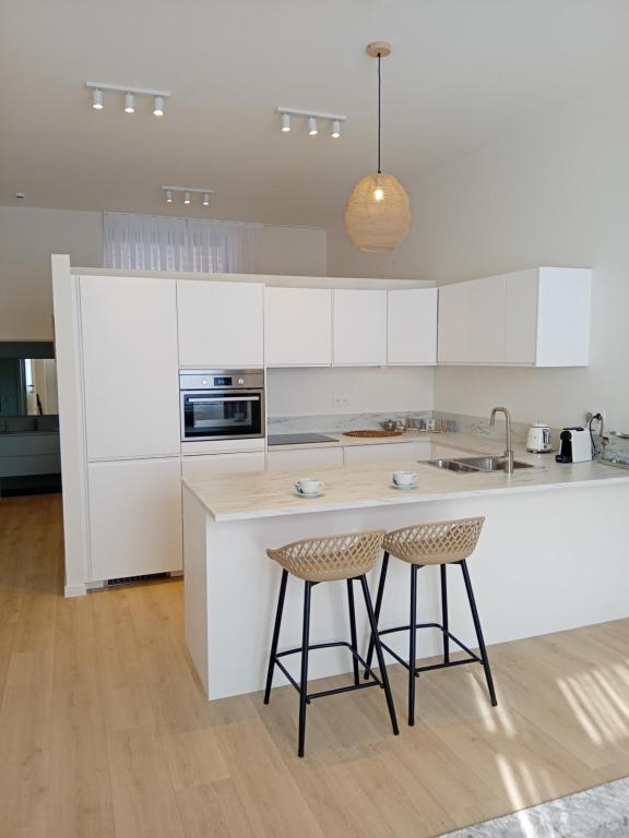 a kitchen with white cabinets and two bar stools at ApartmentJacob1 in Antwerp