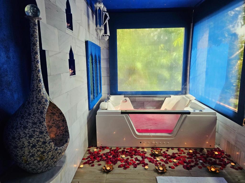 baño con bañera con ventana y flores en Casa completa para parejas jacuzzi piscina y wifi cerca al Caminito del Rey Málaga España, en Álora
