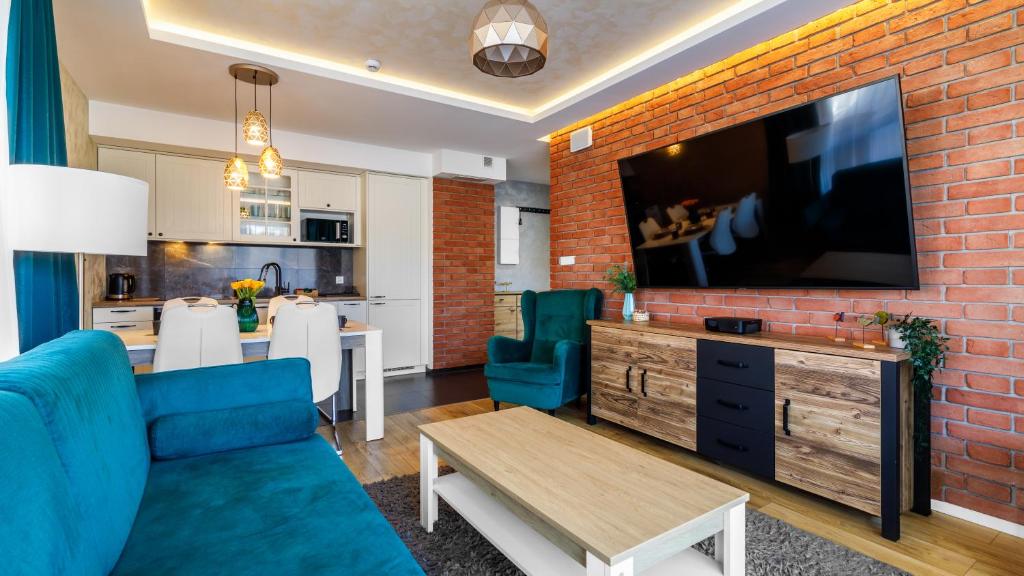 a living room with a blue couch and a brick wall at Comfy Apartments - Morska Bryza in Gdańsk