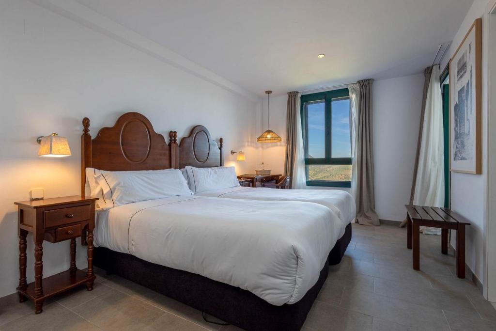 a bedroom with a large bed and a large window at Hotel Tugasa Arco de la Villa in Zahara de la Sierra