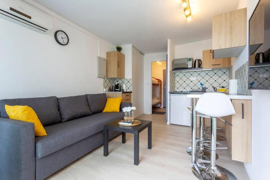 un salon avec un canapé et une table et une cuisine dans l'établissement Chez Chantal - Charmant studio avec piscine proche des plages, à La Grande Motte