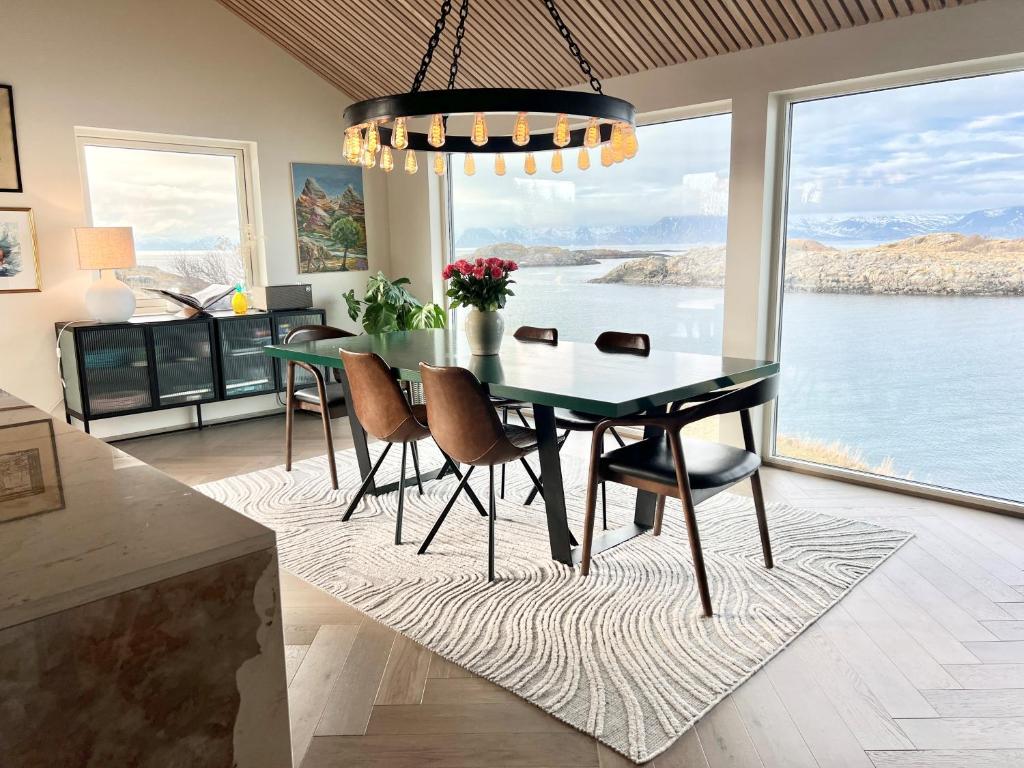 uma sala de jantar com mesa e cadeiras e uma grande janela em Villa Bluebird em Henningsvær