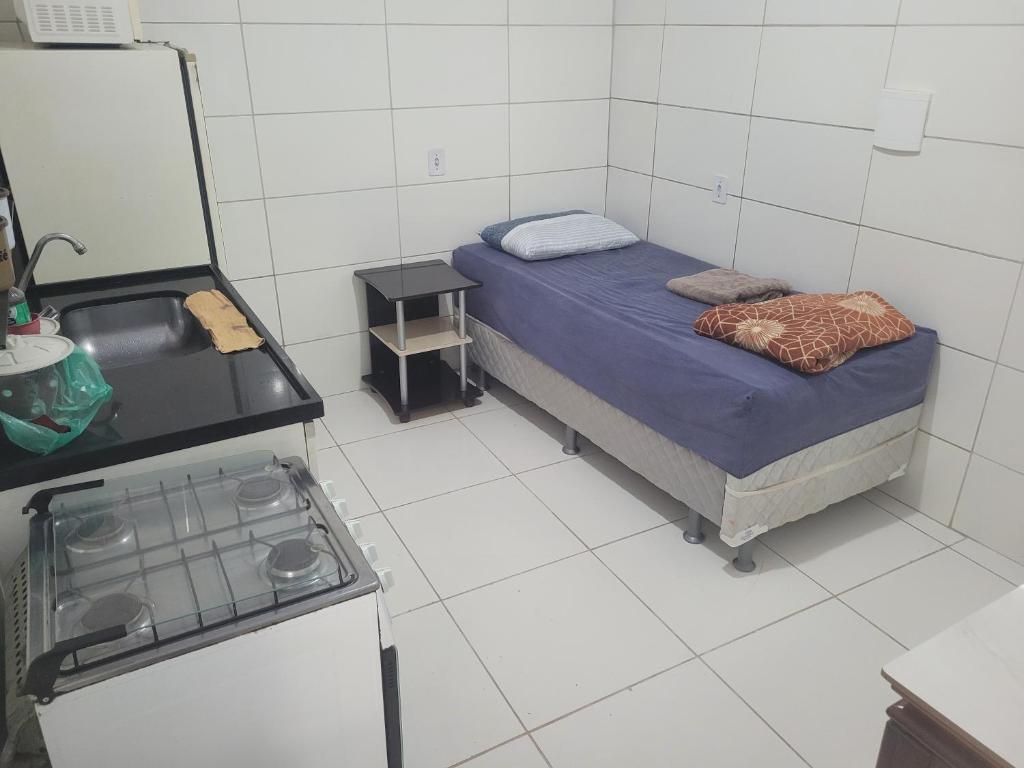 a small room with a bed and a stove at Hospedaria cmc unidade 02 in Riacho Fundo