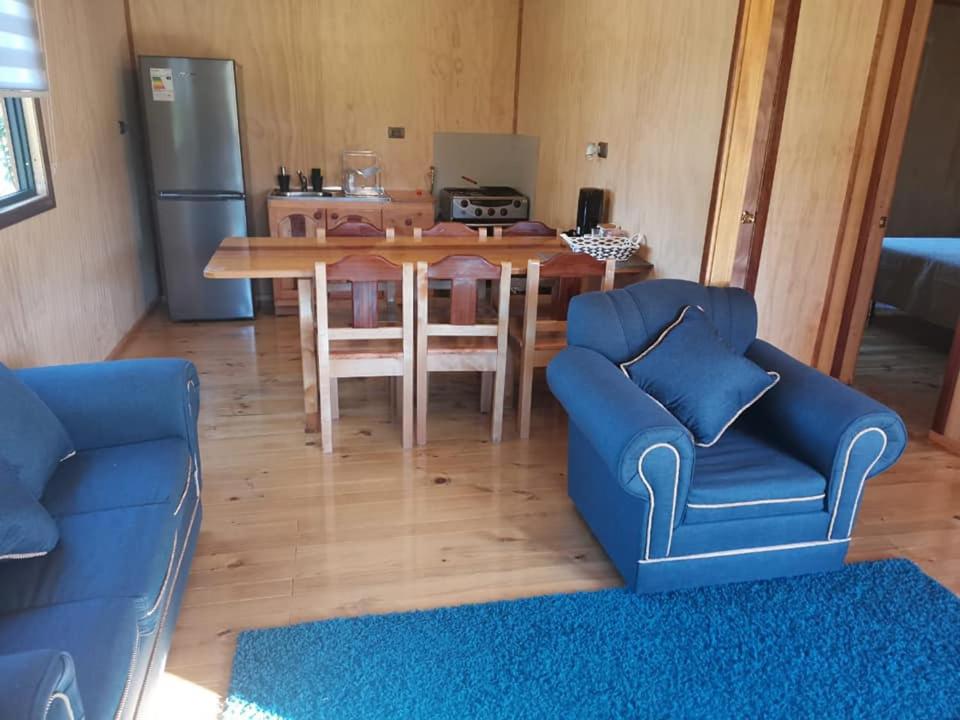 sala de estar con mesa y sofá azul en Cabañas Ancestral, en Hornopirén
