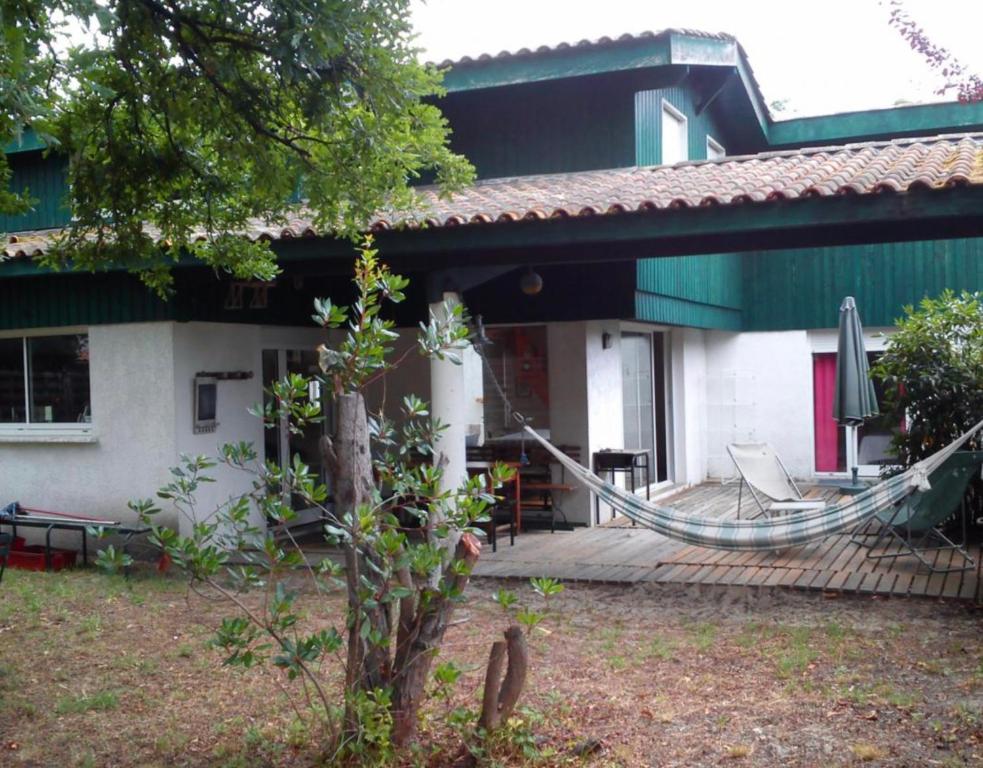 une maison avec une terrasse dotée d'un hamac. dans l'établissement Village de l'herbe réf 2094, à Lège-Cap-Ferret