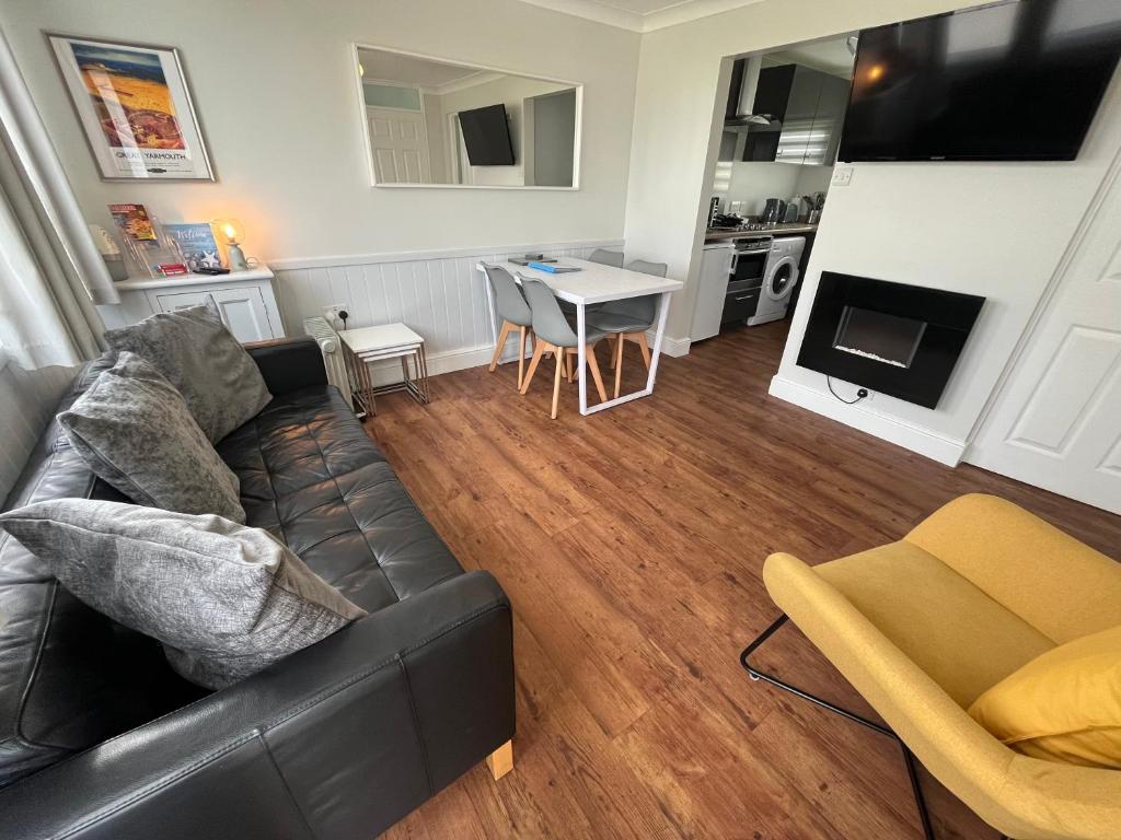 a living room with a black couch and a table at Beachcomber, Sunbeach, Scratby - Two bed chalet, sleeps 4, FREE Wi-Fi, FREE club passes, FREE swimming and pet friendly in Scratby