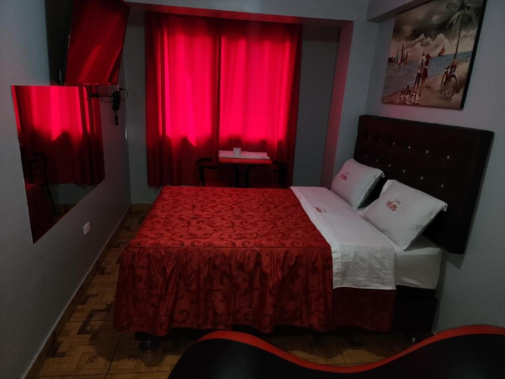 1 dormitorio con cortinas rojas y 1 cama con manta roja en hostal paris, en Lima