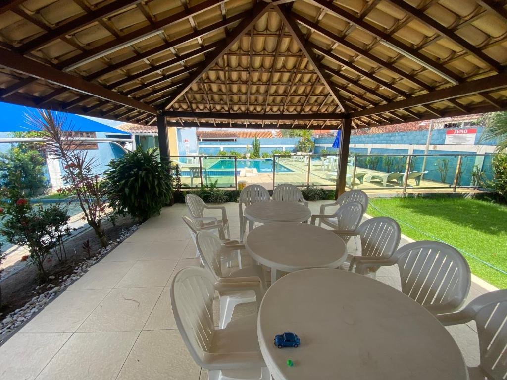 une rangée de tables et de chaises blanches sous un pavillon dans l'établissement Casa em condomínio fechado Amaralina, à Porto Seguro