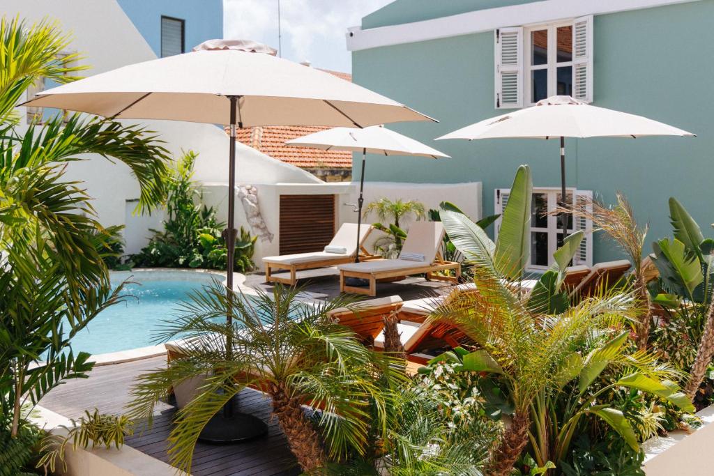 a patio with umbrellas and a swimming pool at Pietermaai Oasis in Willemstad