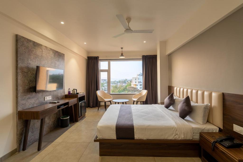 コールハープルにあるThe Living Hub Business Hotel, Kolhapurのベッドとデスクが備わるホテルルームです。