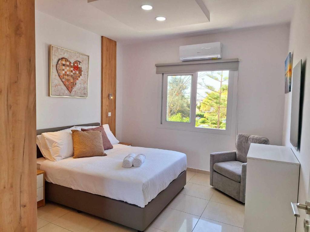 a bedroom with a bed and a window and a chair at Stylish Apt Kato Paphos Close to Beach & Vibrant Harbor Life in Paphos
