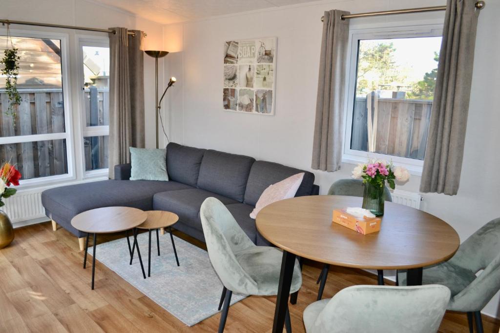 a living room with a couch and a table and chairs at Chalet 27 in Zandvoort