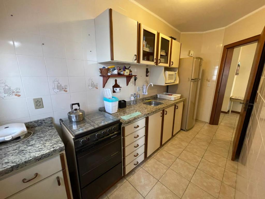 eine kleine Küche mit einem Herd und einem Kühlschrank in der Unterkunft Apartamento a uma quadra da praia in Capão da Canoa