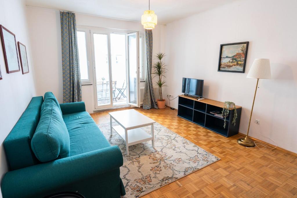 ein Wohnzimmer mit einem blauen Sofa und einem Tisch in der Unterkunft Central Living Apartments - Staatsoper in Wien